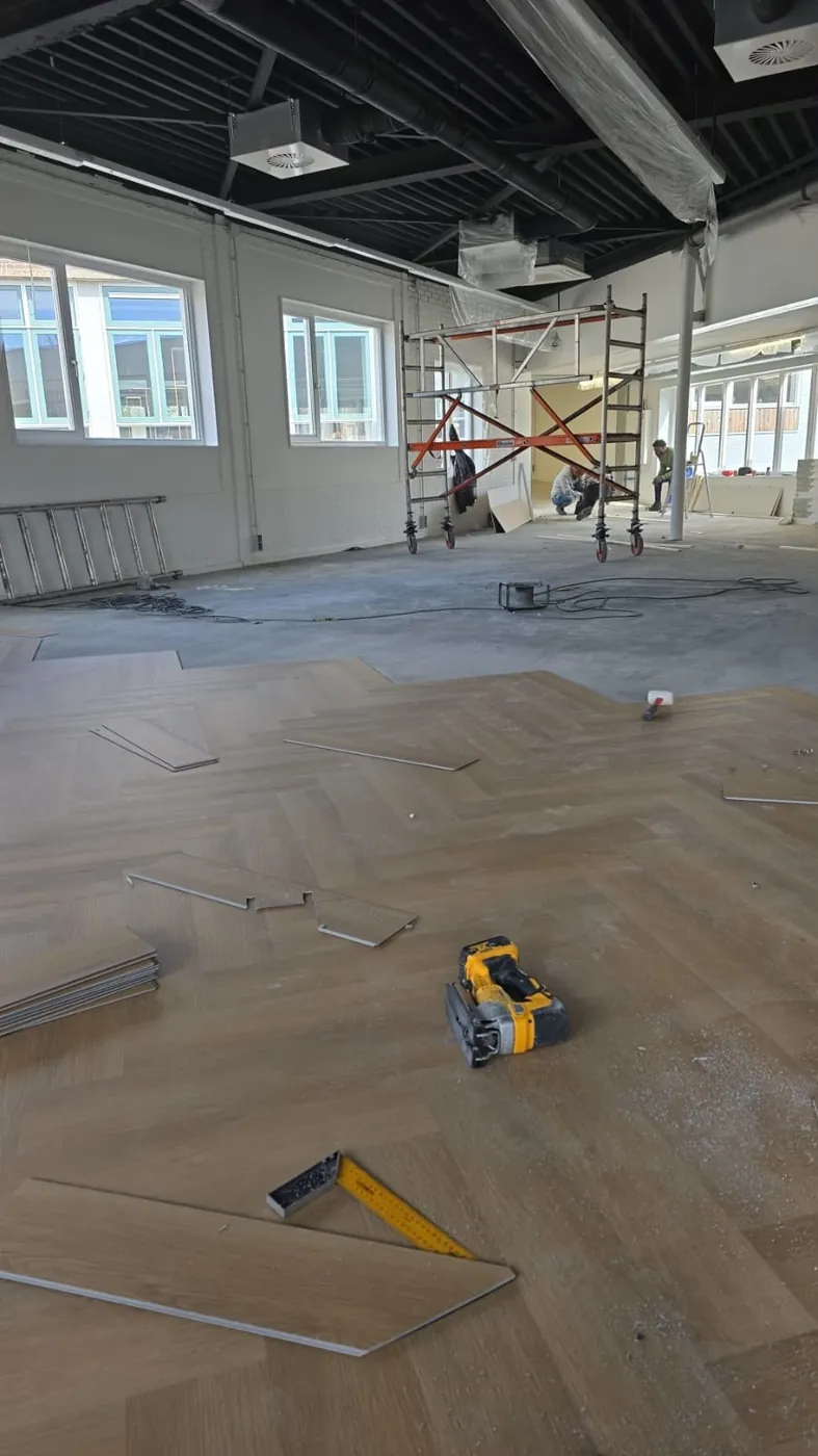 Kale ondergrond na het verwijderen van de oude vloer, met de nieuwe visgraatvloer deels gelegd